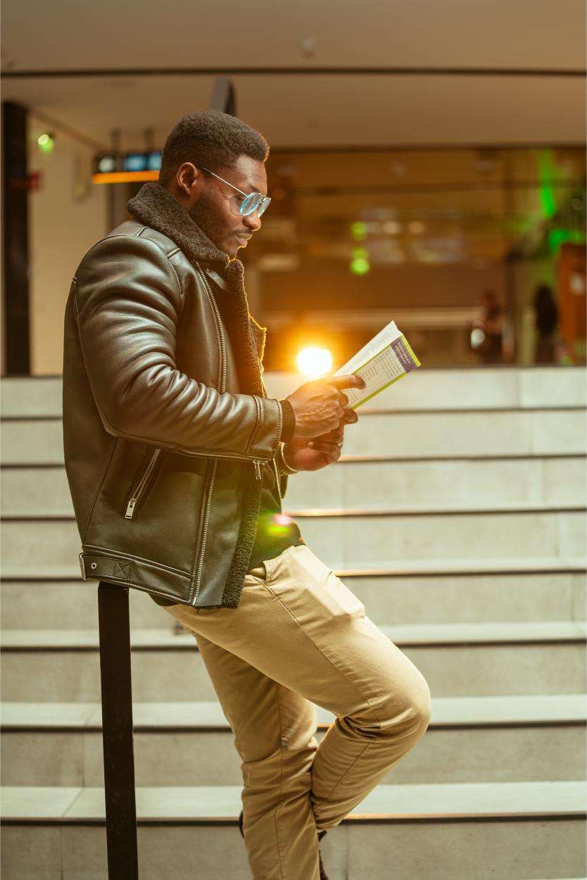 Man in leather jacket reading book on stairs, captured by Photographer Helsinki, offering custom photography and customized photo solutions