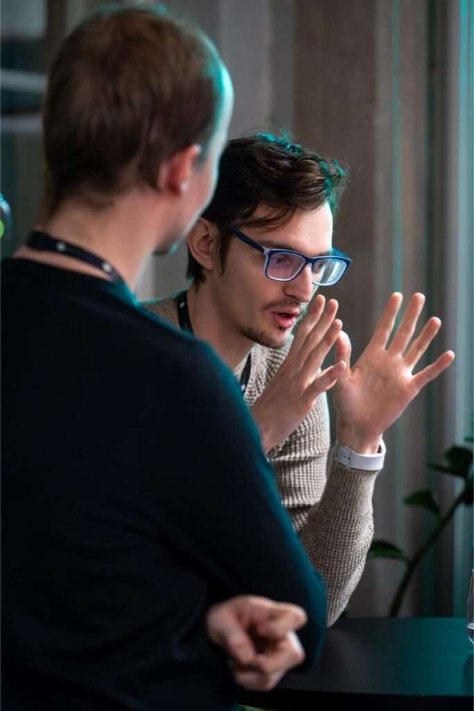 Two men engaged in a conversation indoors at a corporate event in Helsinki