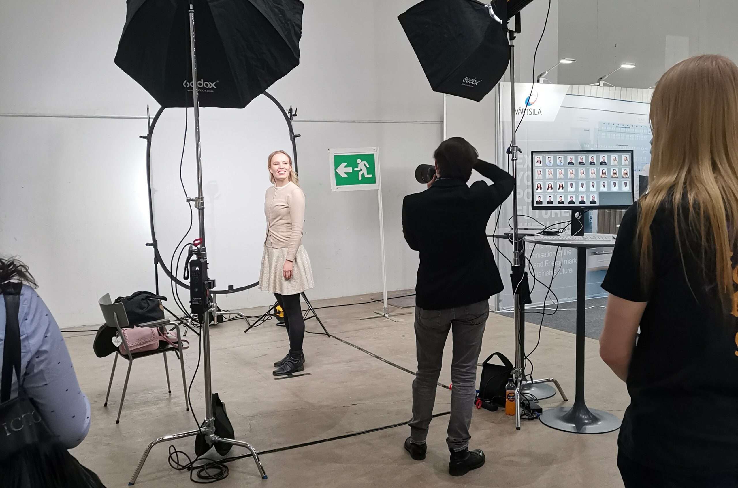 Photographer in Helsinki taking pictures of a smiling woman in a studio, utilizing a headshot photobooth for professional results.