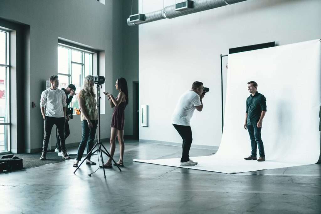 A photographer in Helsinki capturing a man's portrait in a studio setting, using a headshot photobooth for professional photos.