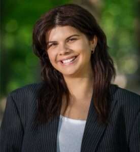 Happy young woman smiling outdoors in business attire.